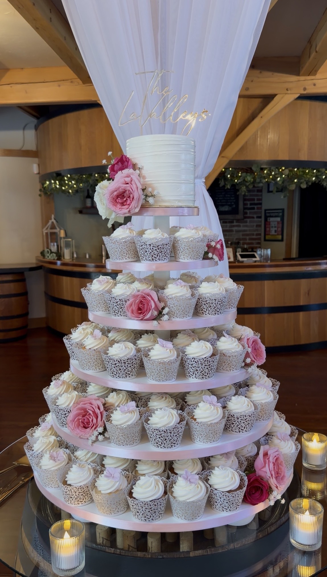 The tiered cupcake tower with "The LaValleys" script sign and fresh rose accents