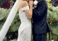 Bride and groom embrace and smile at the camera.
