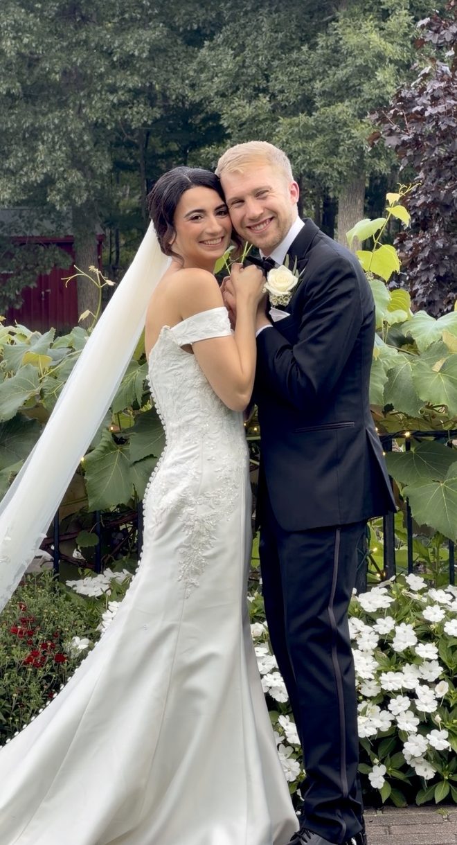 Bride and groom embrace and smile at the camera.