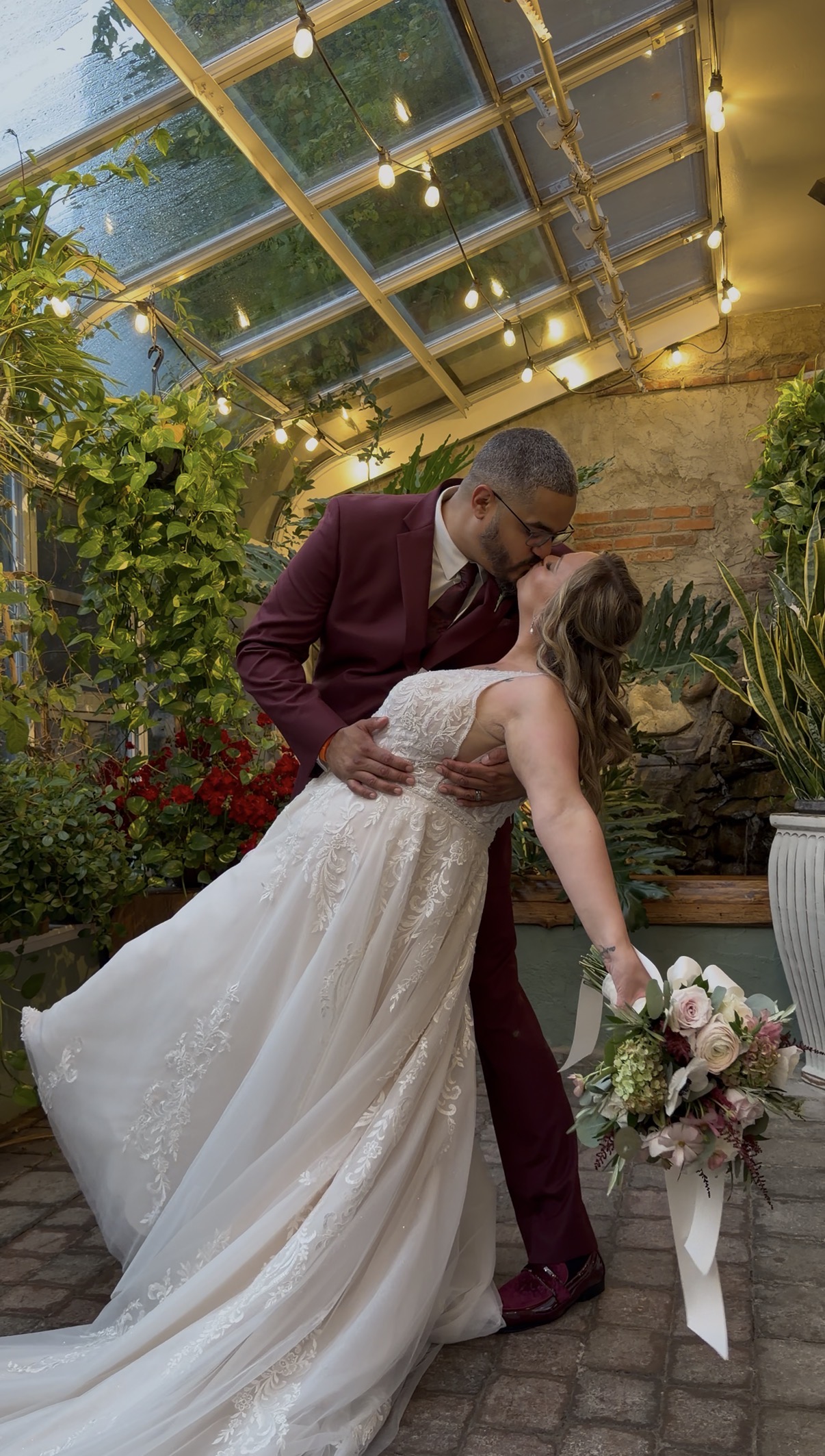 "Adrian dips Emily for a kiss on the stone floor of the Zorvino greenhouse as her lace gown train fans out and her bouquet trails ivory ribbon"