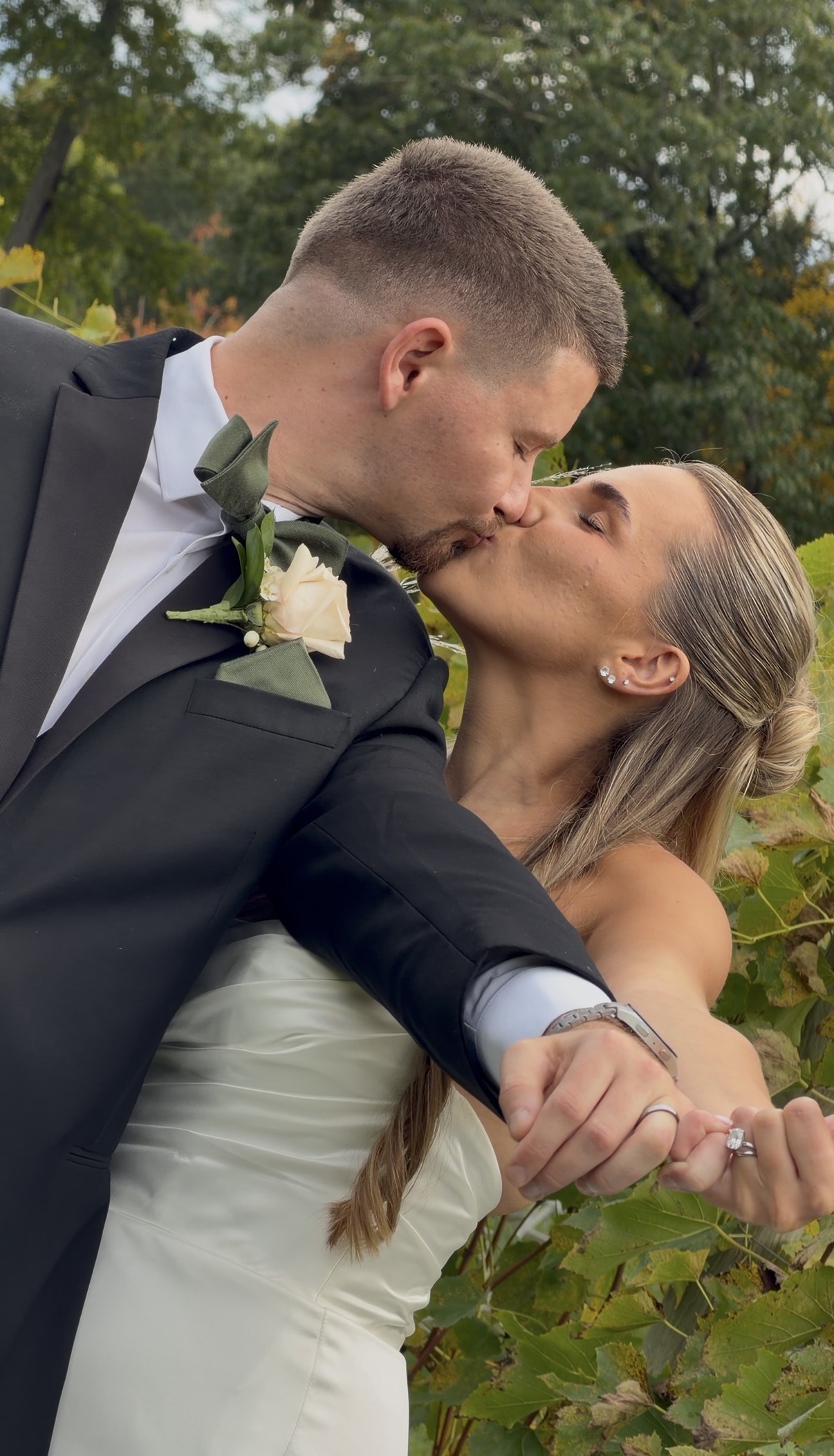 Sophia and Scott kiss in the Zorvino vineyard with their hands joined and arms extended to show their wedding rings.