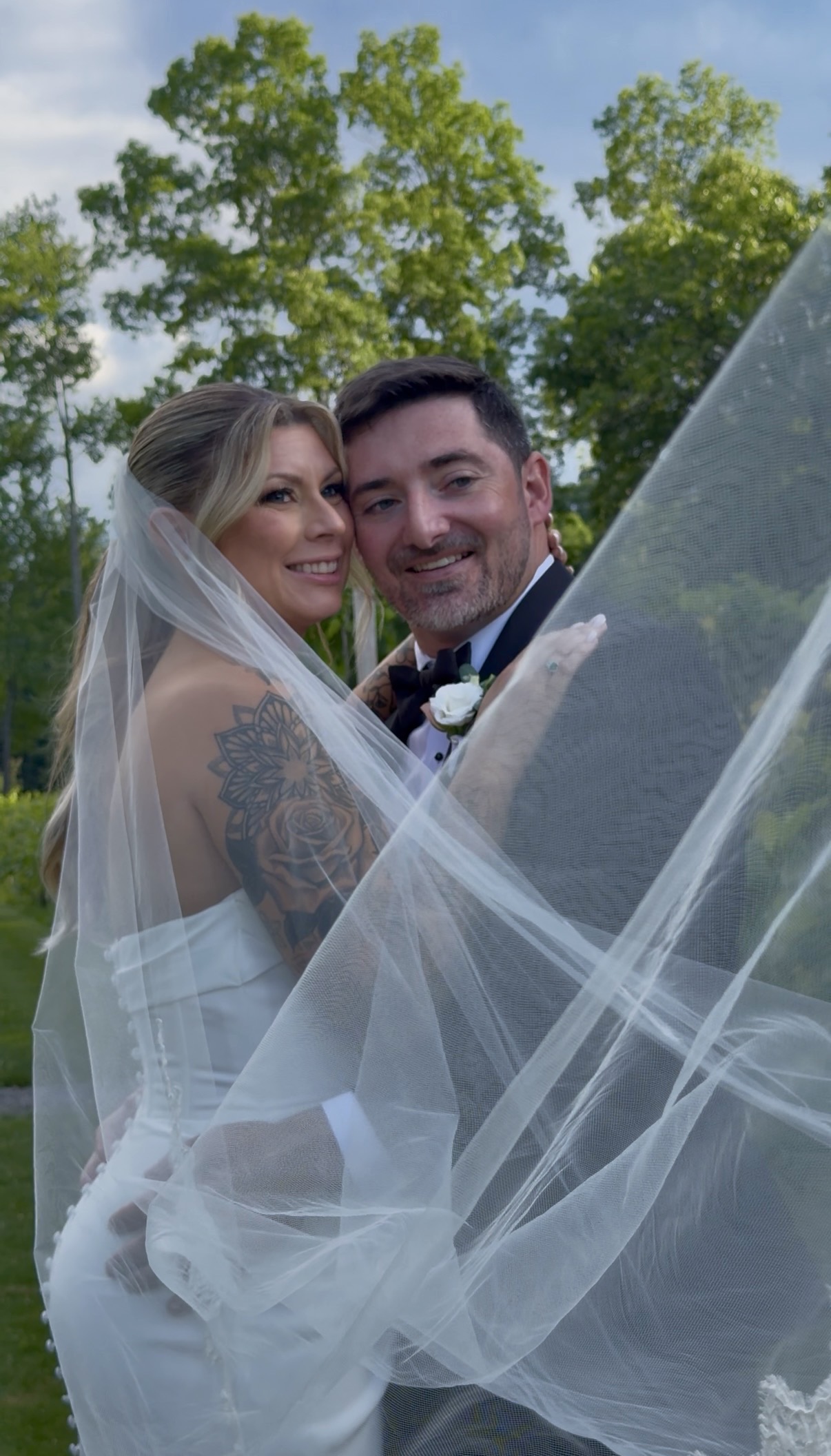 Bride and groom wrapped in the bride's veil.