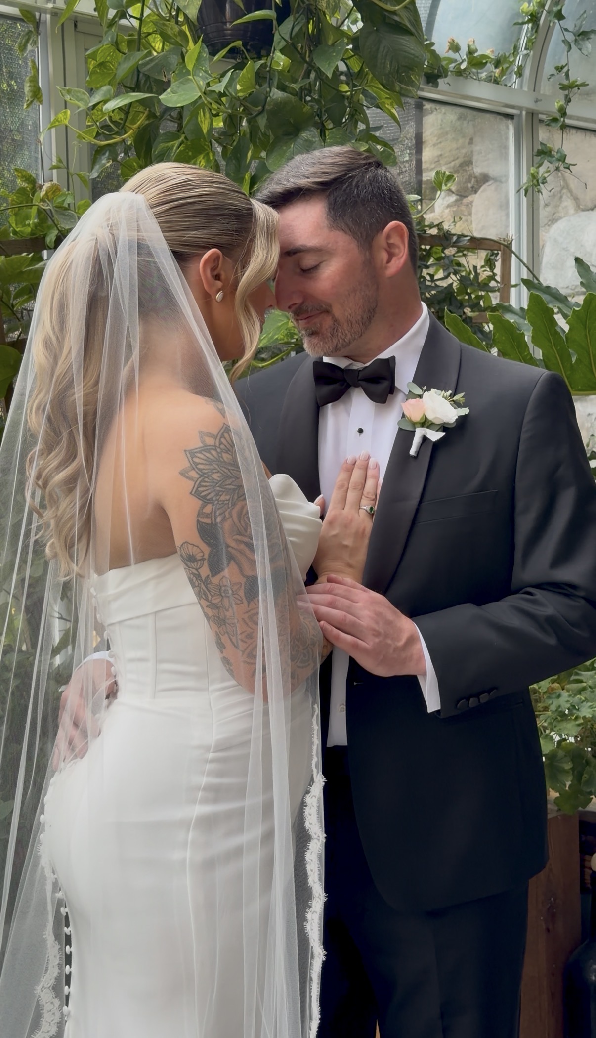 A bride and groom touch foreheads with their eyes closed.