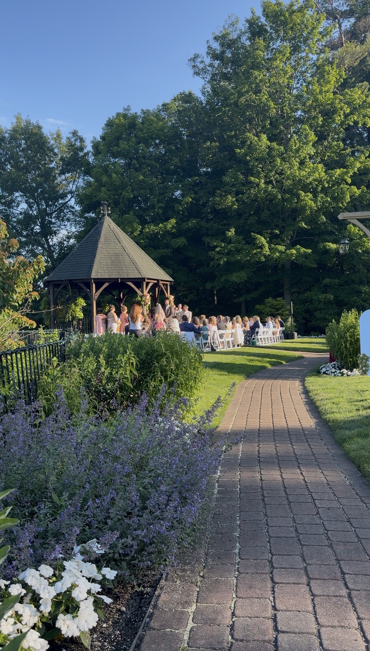 Wedding guests watch the ceremony in front of the gazebo.