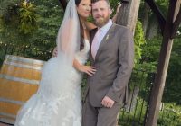 A bride and groom pose for the camera at the gazebo.