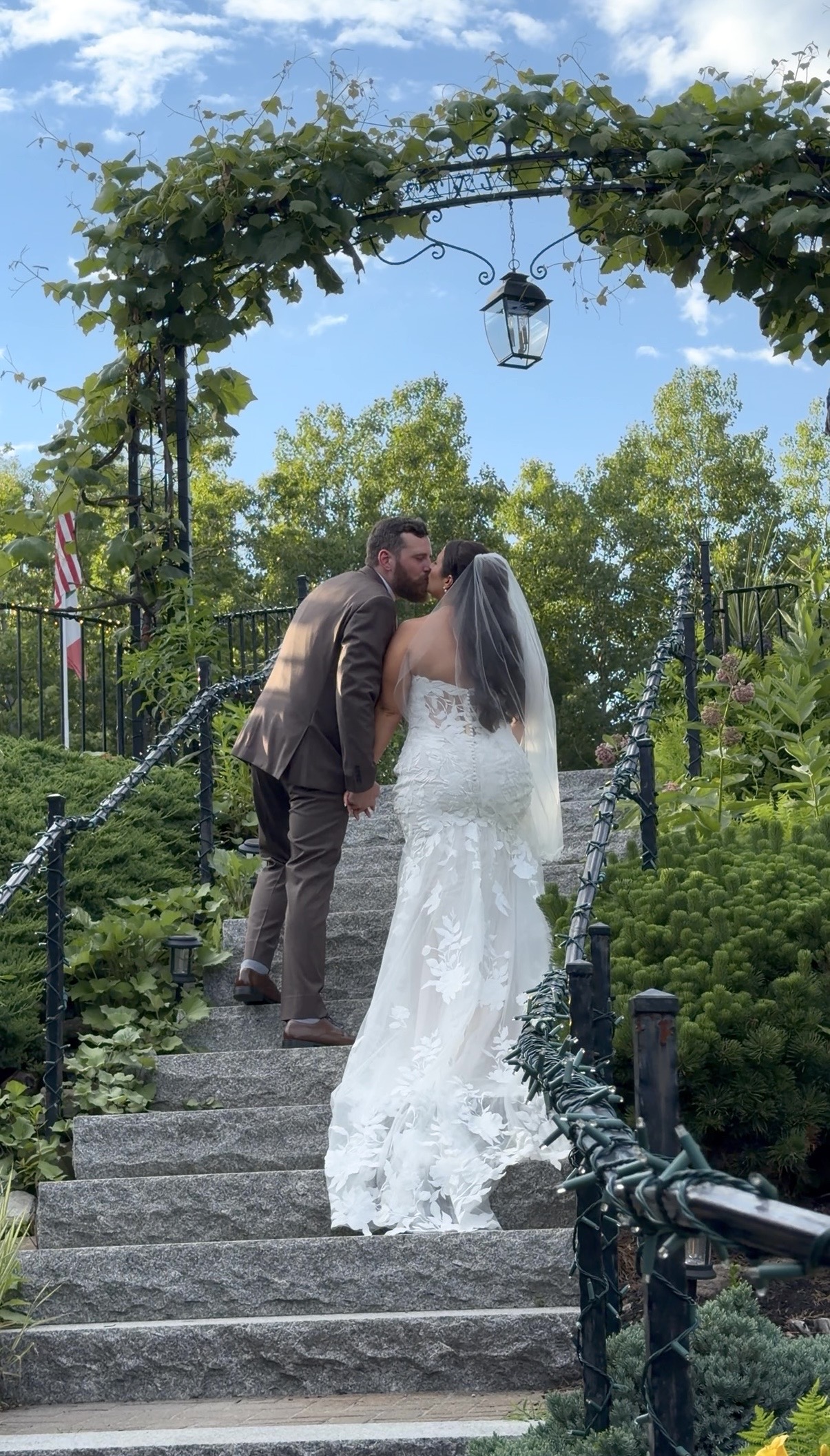 A bride and groom walking up stairs kissing.