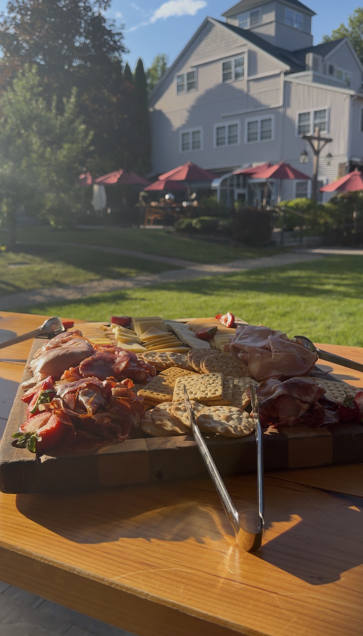 A charcuterie board on the patio, red umbrellas beyond.