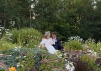 A bride and groom look at each other in a garden full of flowers.