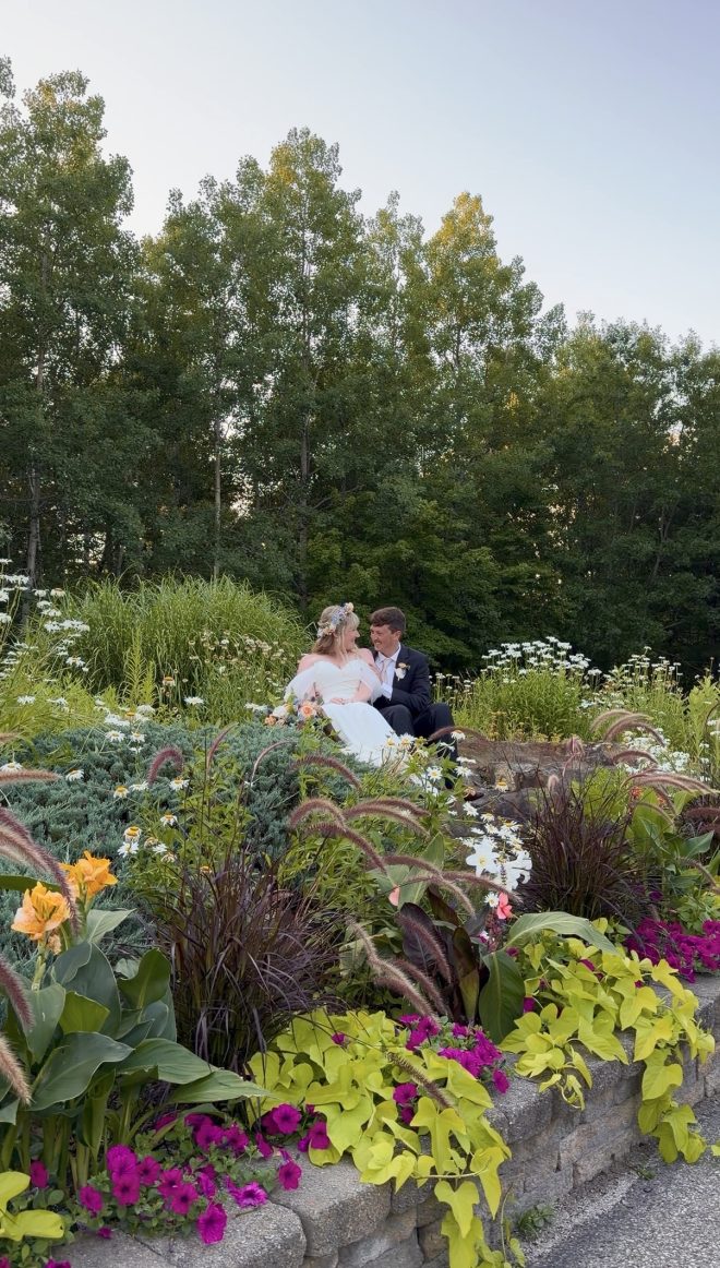A bride and groom look at each other in a garden full of flowers.