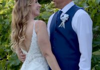 A bride and groom hold hands as they face each other, smiling.