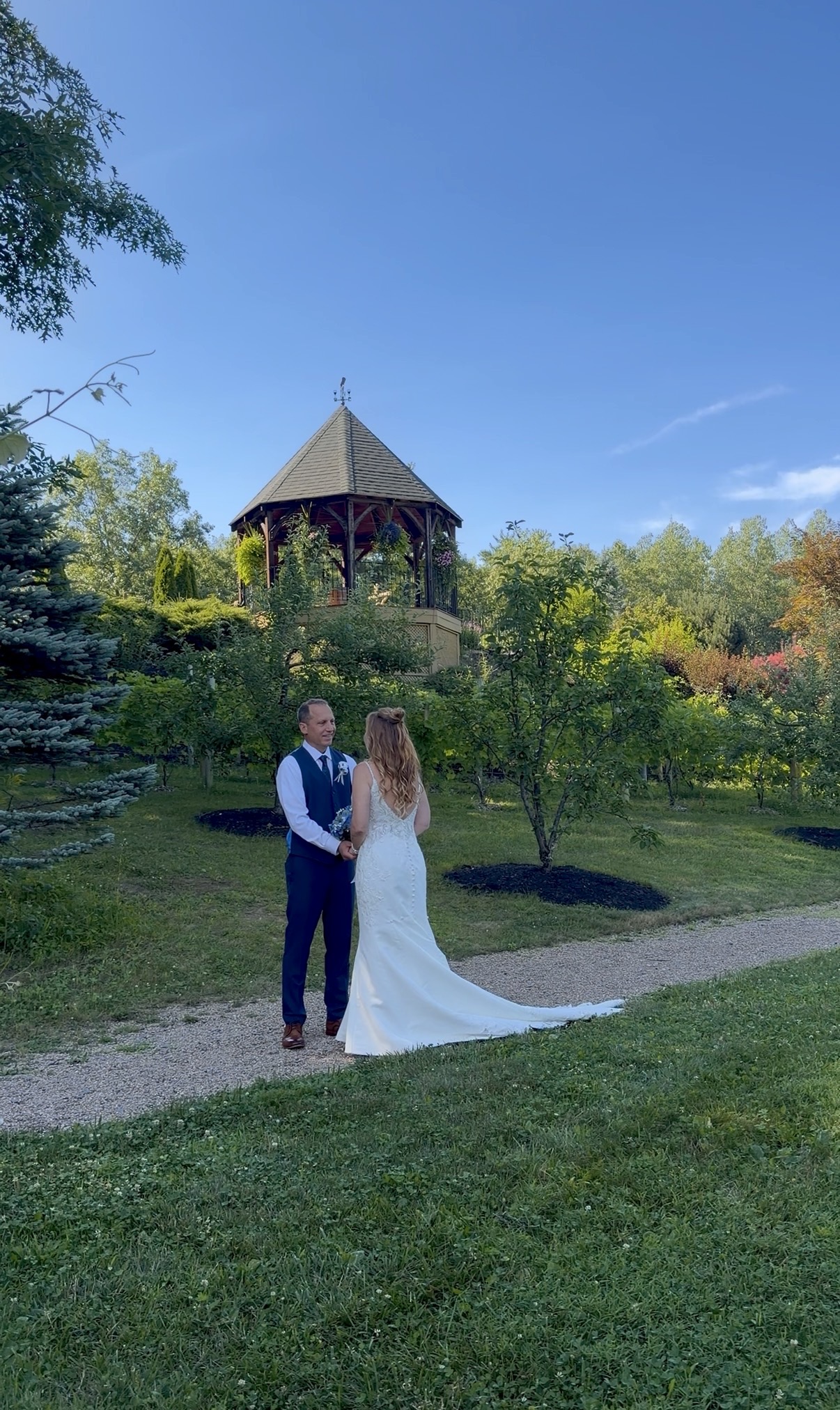 Bride and groom face each other with the gazebo in the background.