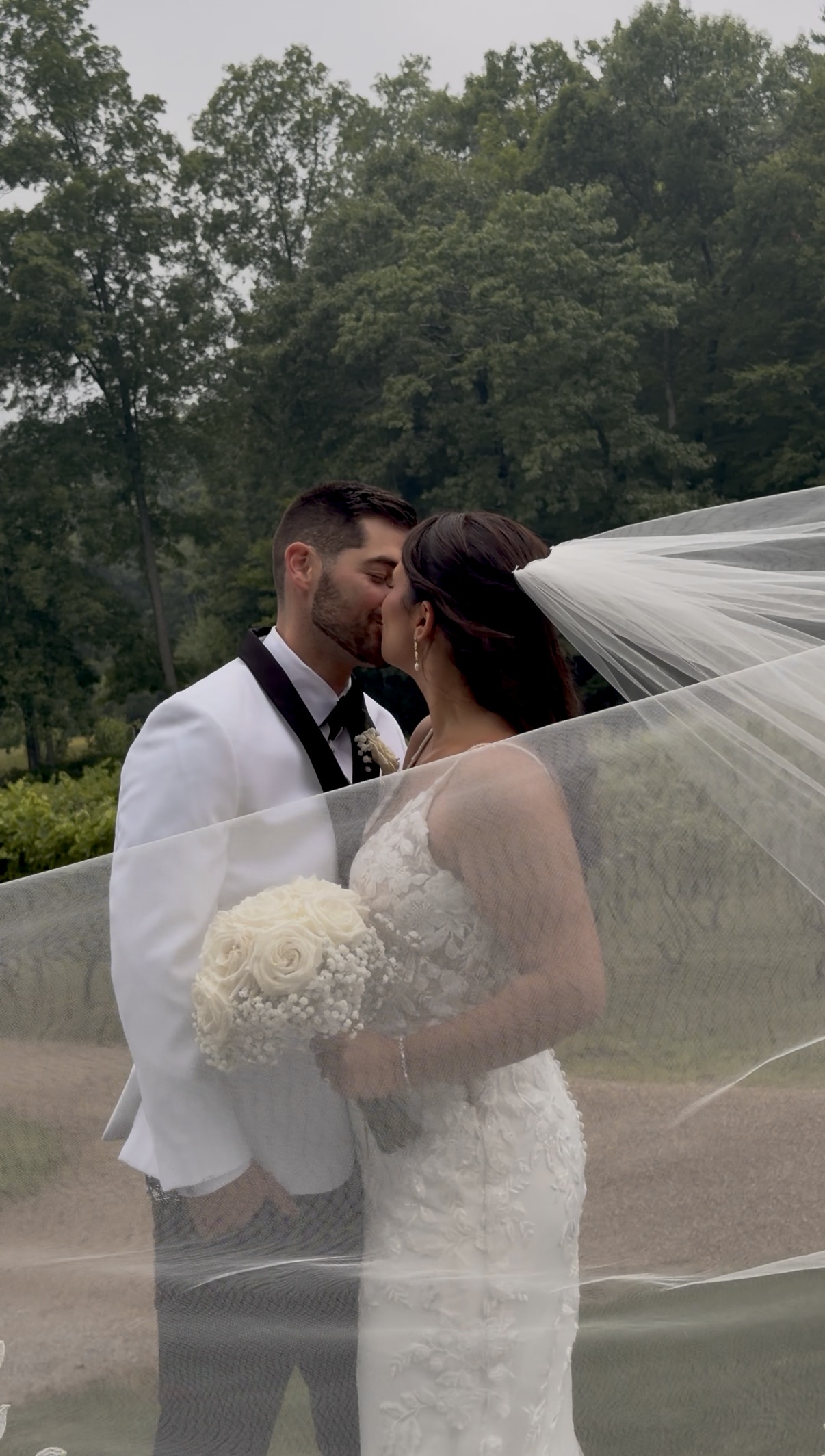 Bride and groom kiss behind the sheer veil.