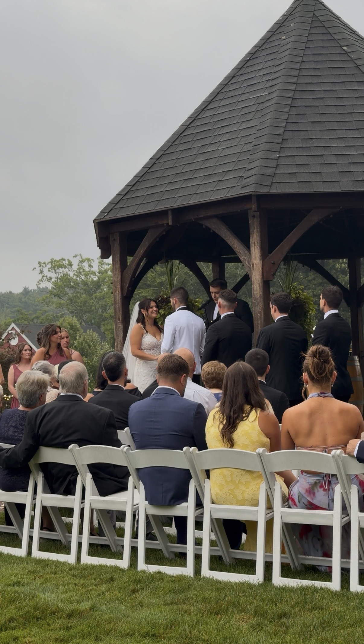 Bride and groom at the altar in front of the gazebo as guests watch the ceremony.