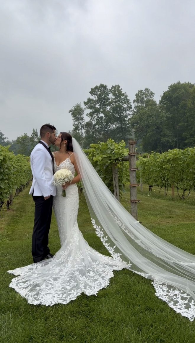 Bride and groom stand together in the vineyard.
