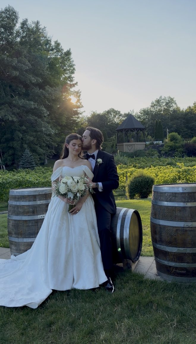 Bride and groom in front of the wine barrels.