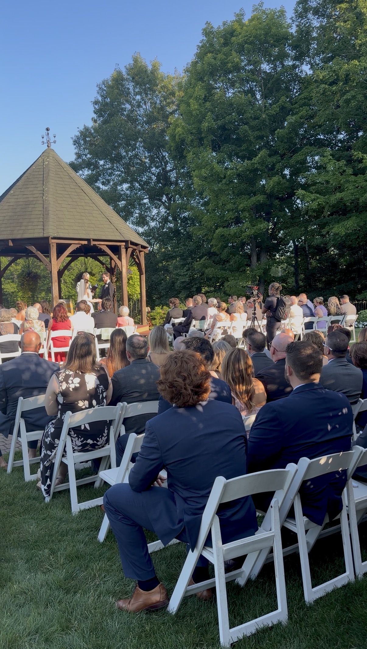 Wedding guests watch the ceremony in front of the gazebo.