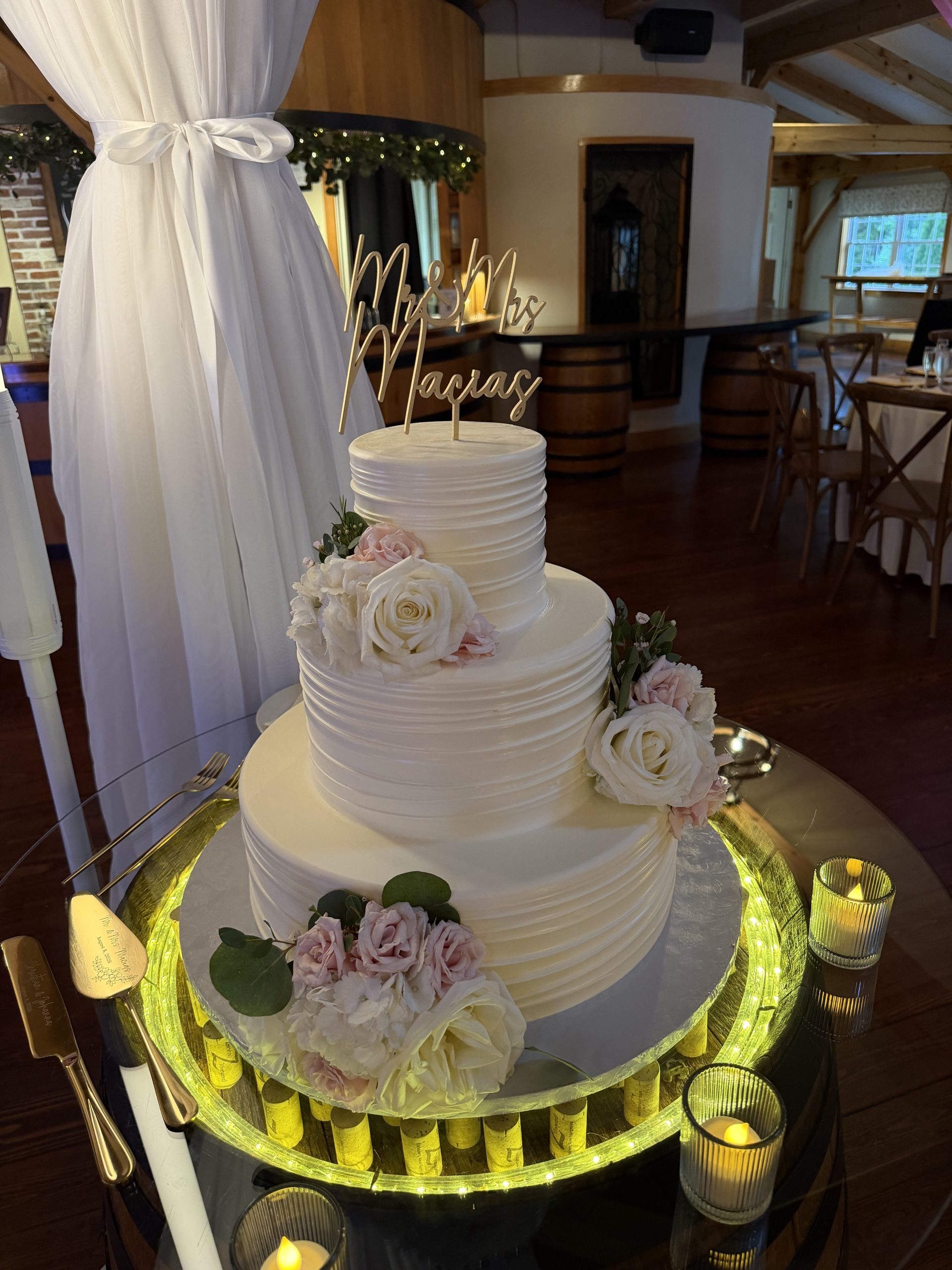 Three-tier buttercream wedding cake with blush roses and a gold Mr and Mrs Macias topper.