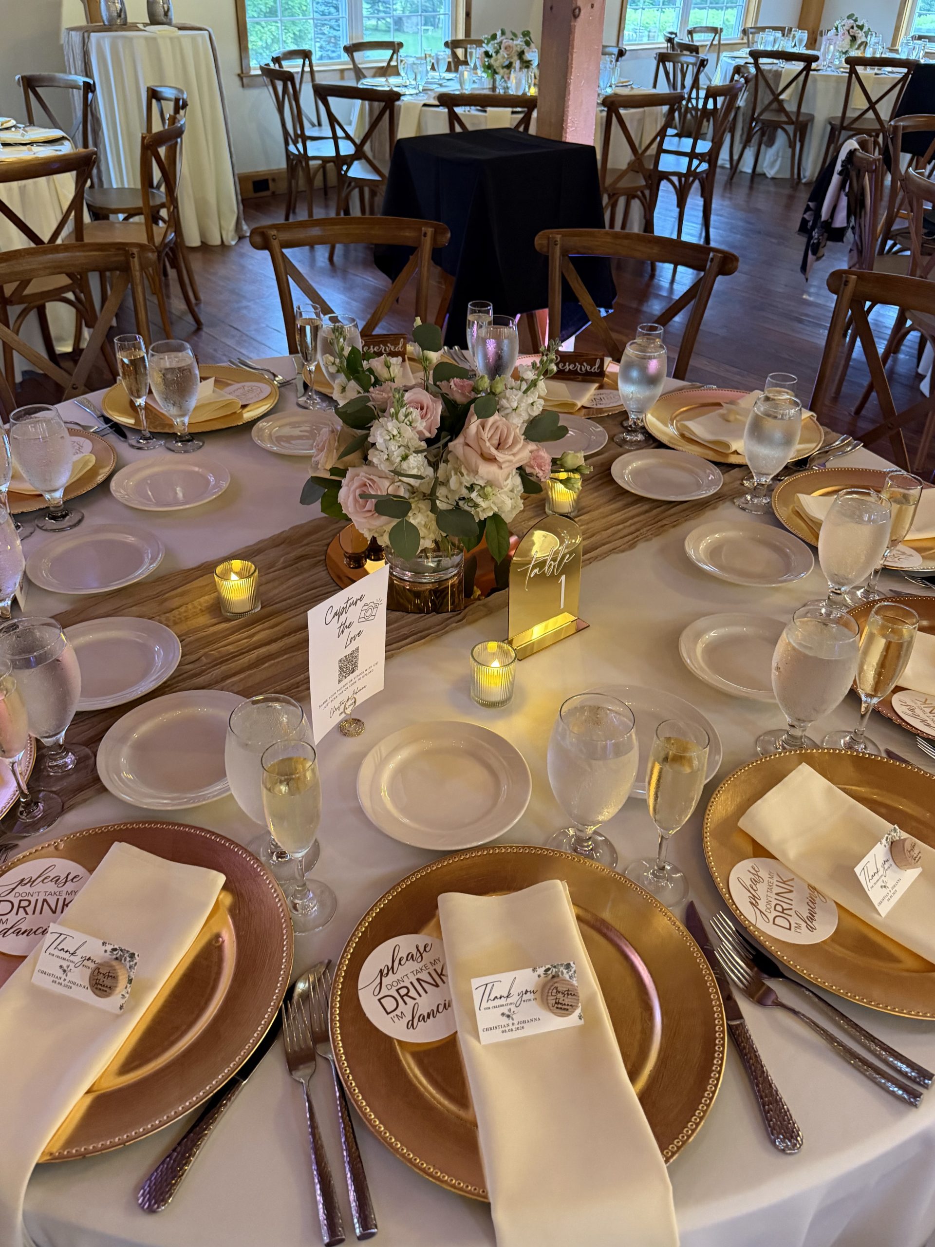 Gold chargers, blush blooms, and gilded table numbers catching the candlelight.
