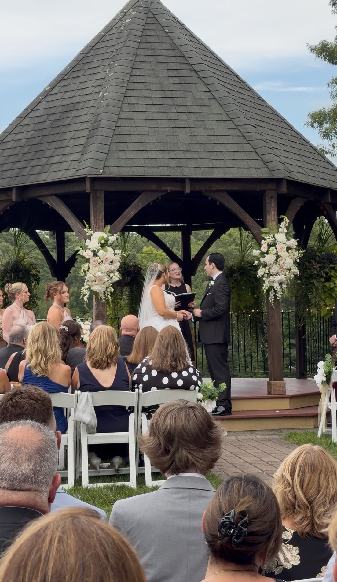 Vows beneath the Outdoor gazebo ceremony framed with ivory and blush roses at a romantic summer vineyard wedding at Zorvino Vineyards.