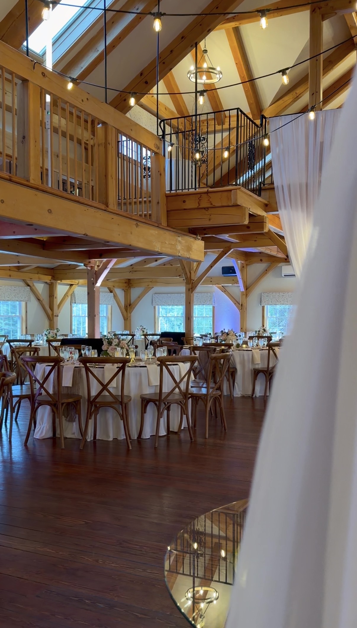 Beams, skylights, and café lights over a room set in gold and champagne. Reception hall at Zorvino Vineyards.