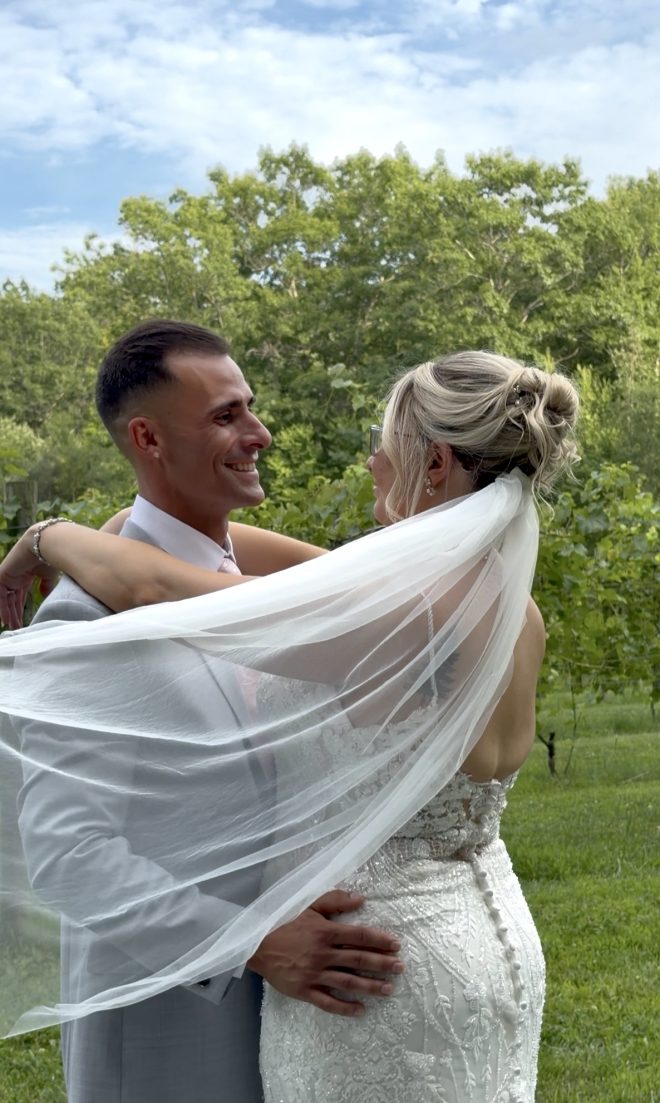 "Kaleigh Whitnell and Dante Abruzzese embracing beneath her veil at Zorvino Vineyards — Sunday summer wedding August 2026 Sandown NH"