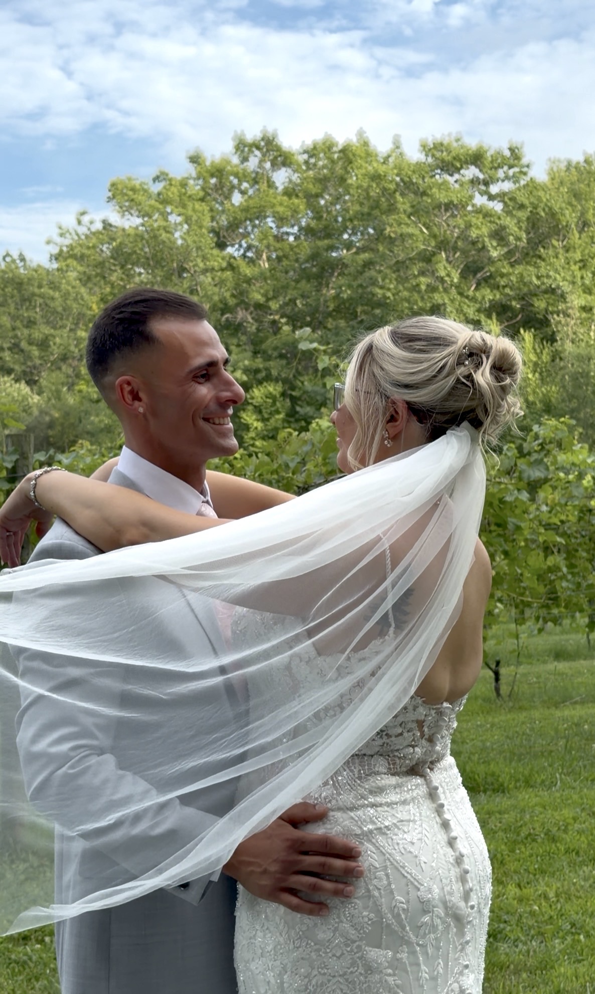 Kaleigh Whitnell and Dante Abruzzese embracing beneath her veil at Zorvino Vineyards — Sunday summer wedding August 2026 Sandown NH