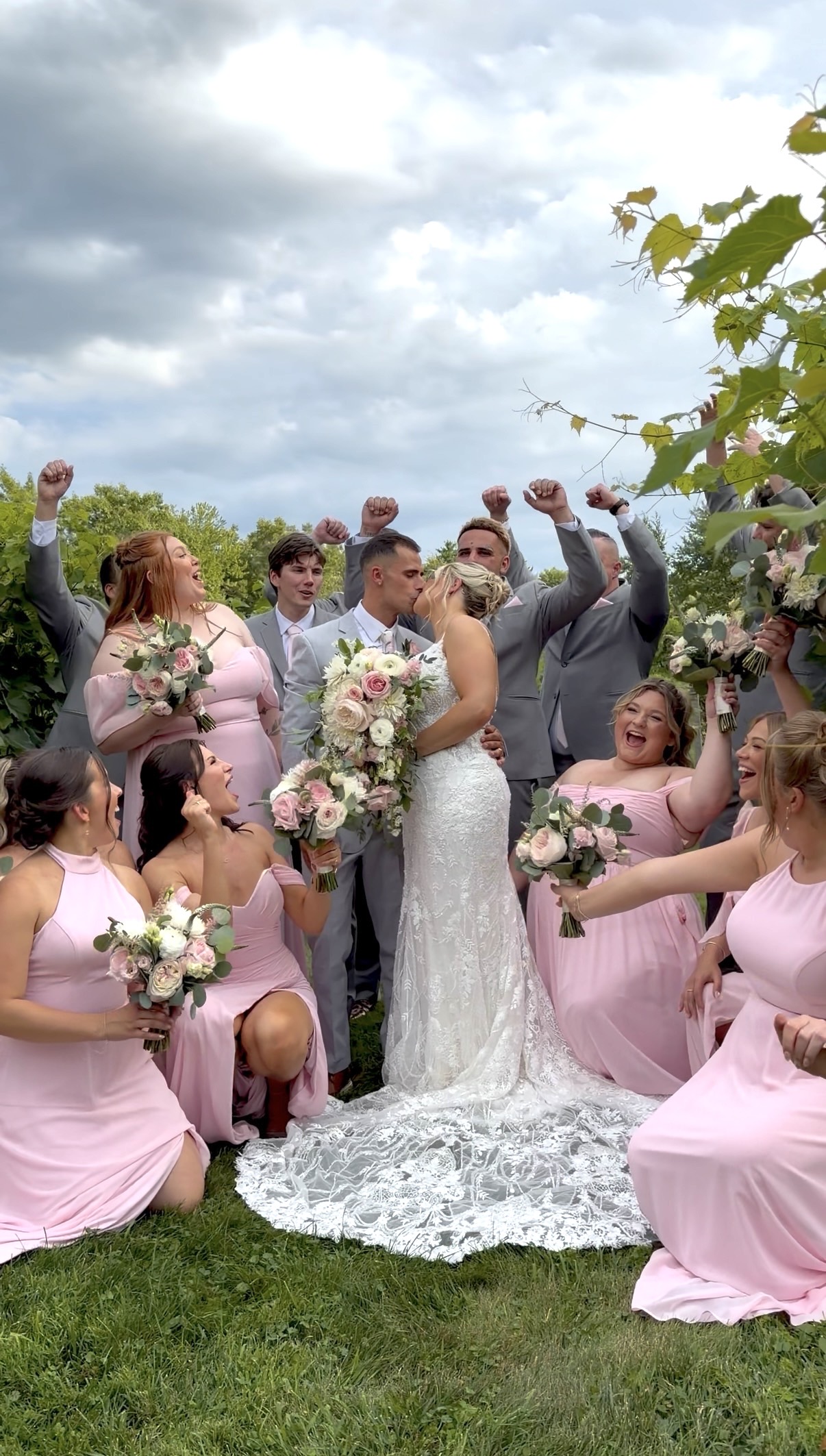 Fourteen-person wedding party celebrating with the bride and groom in pink and grey