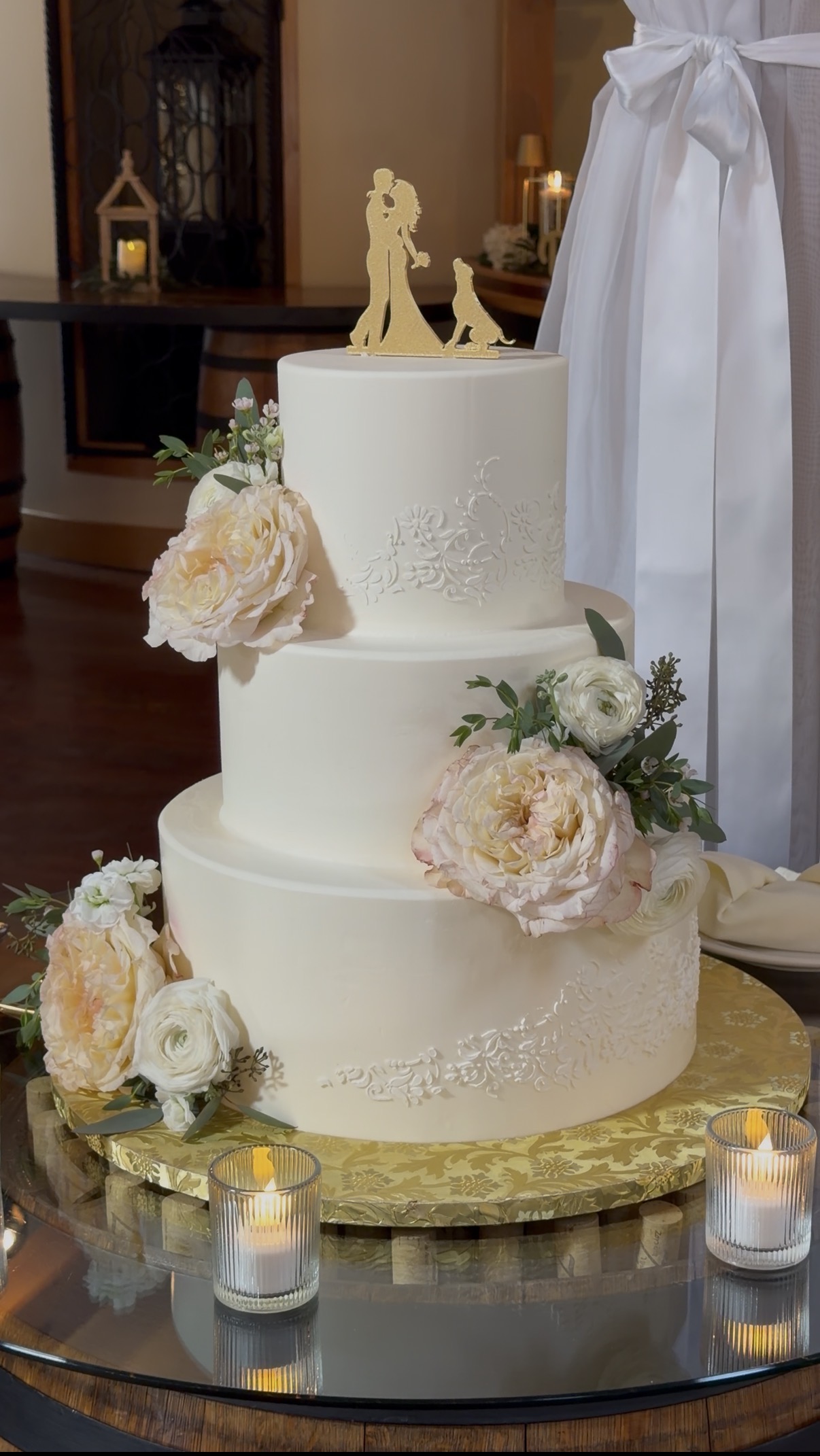 Three-tier ivory wedding cake with blush garden roses and a dog-inclusive cake topper by Chickadee Hill Cakes