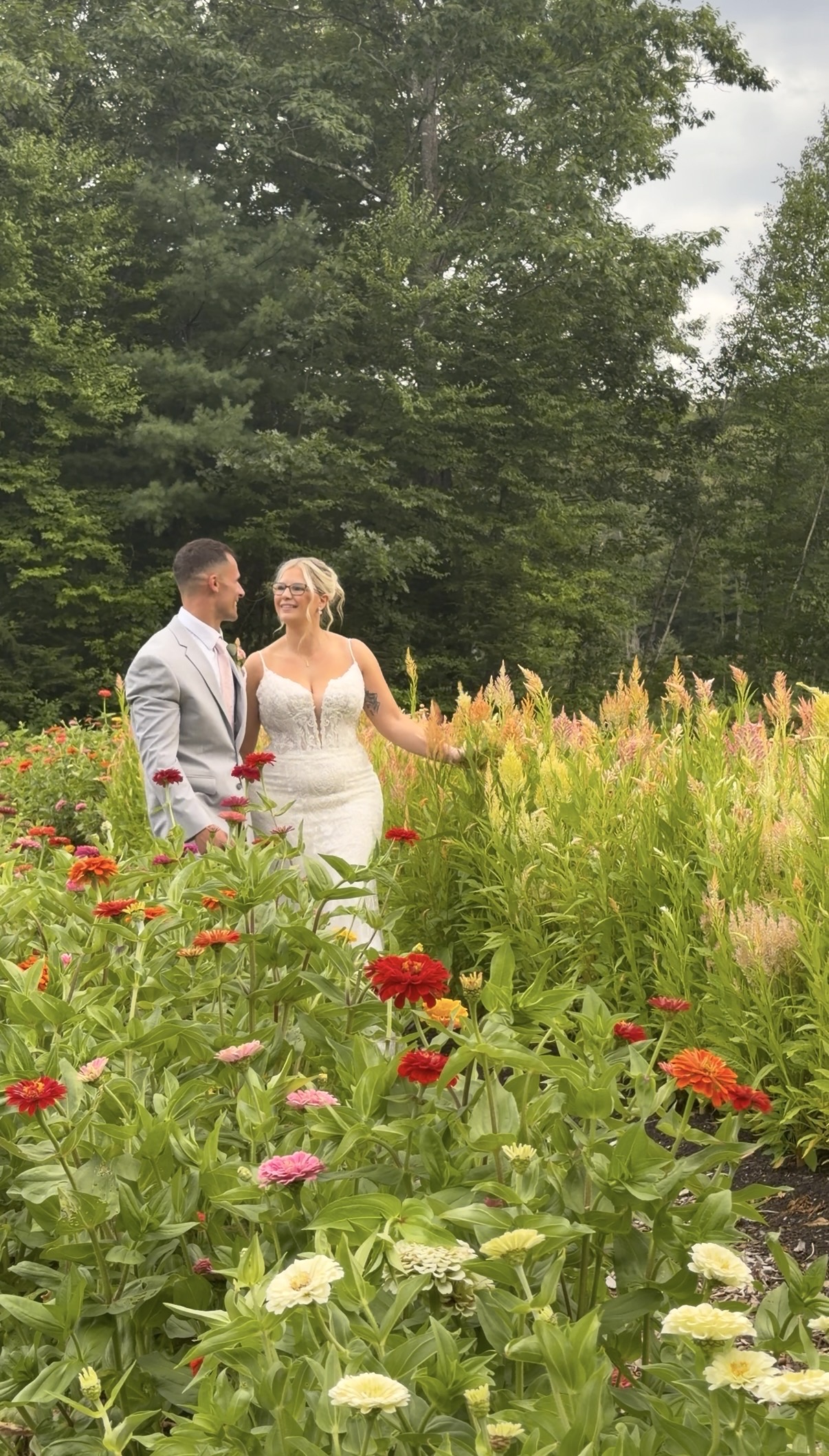 Bride and groom walking through a flower field at golden hour
