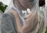 "Christie Raymond and Nick Millett kissing under the bride's veil at Zorvino Vineyards — summer wedding August 2026 Sandown NH"