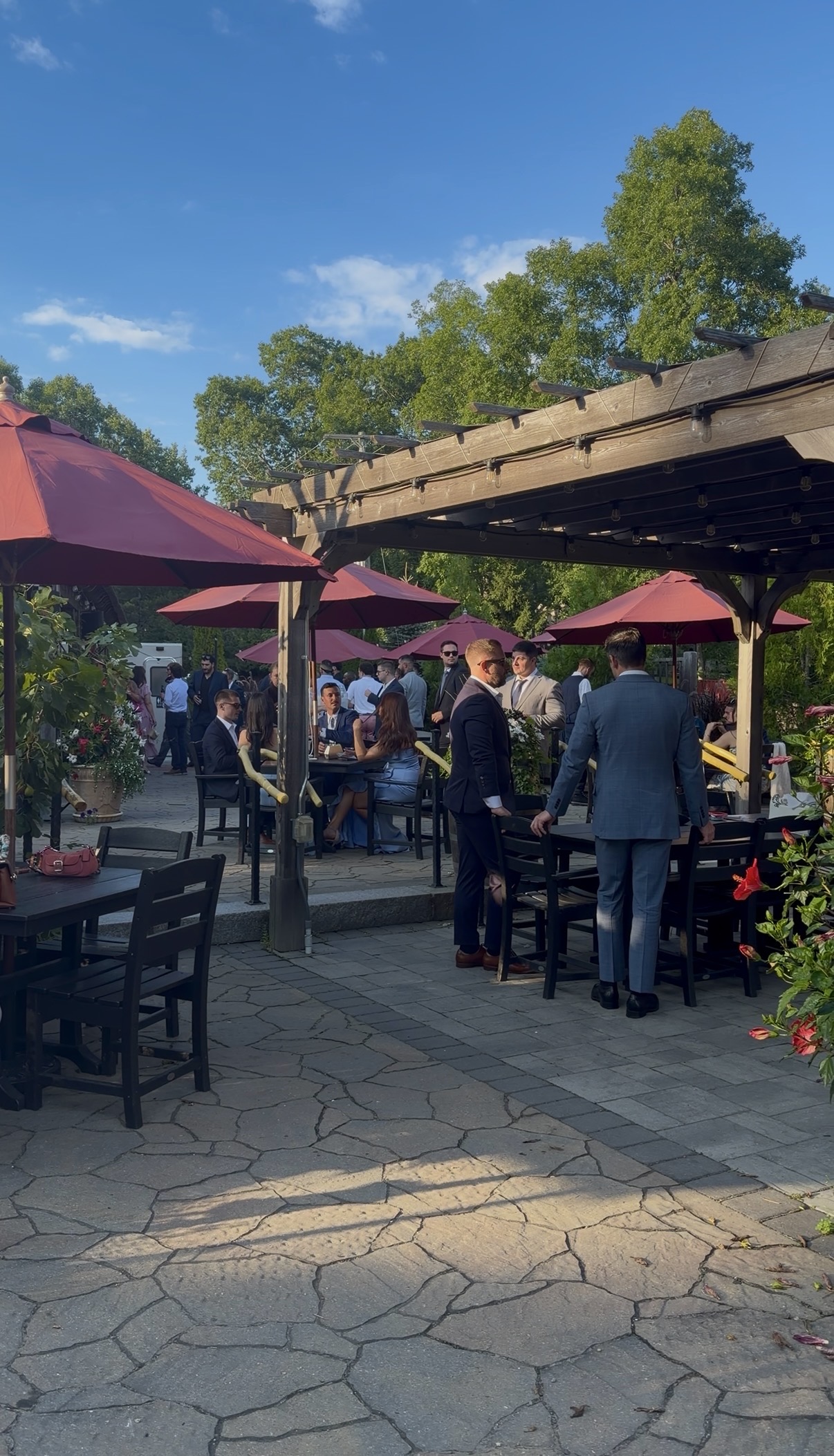 Guests gathered under red umbrellas on the Zorvino patio during cocktail hour
