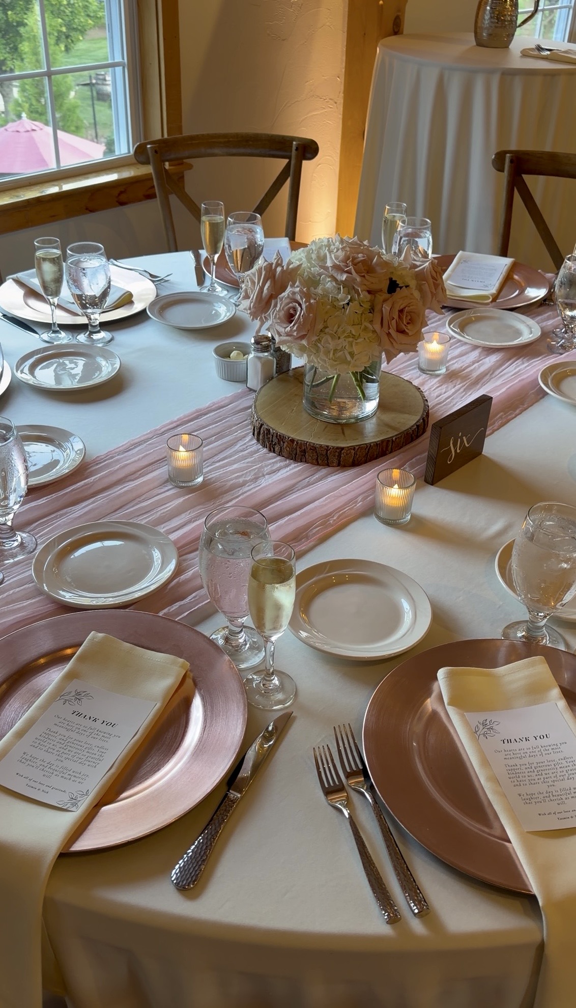The reception tablescape with blush florals, rose gold chargers, and votive candles