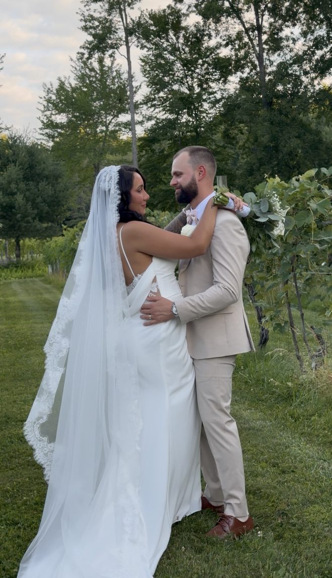 "Yazmin Rosa and Nick LaValley embracing among the vineyard rows at Zorvino Vineyards — Friday summer wedding July 2026 Sandown NH"