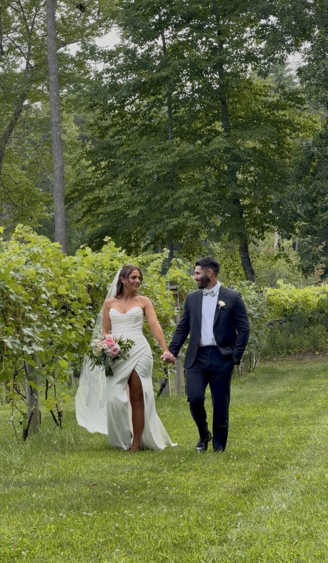 "Annie and Jake holding hands among the vineyard rows at Zorvino Vineyards — a dreamy summer vineyard wedding in Sandown NH, August 2026"