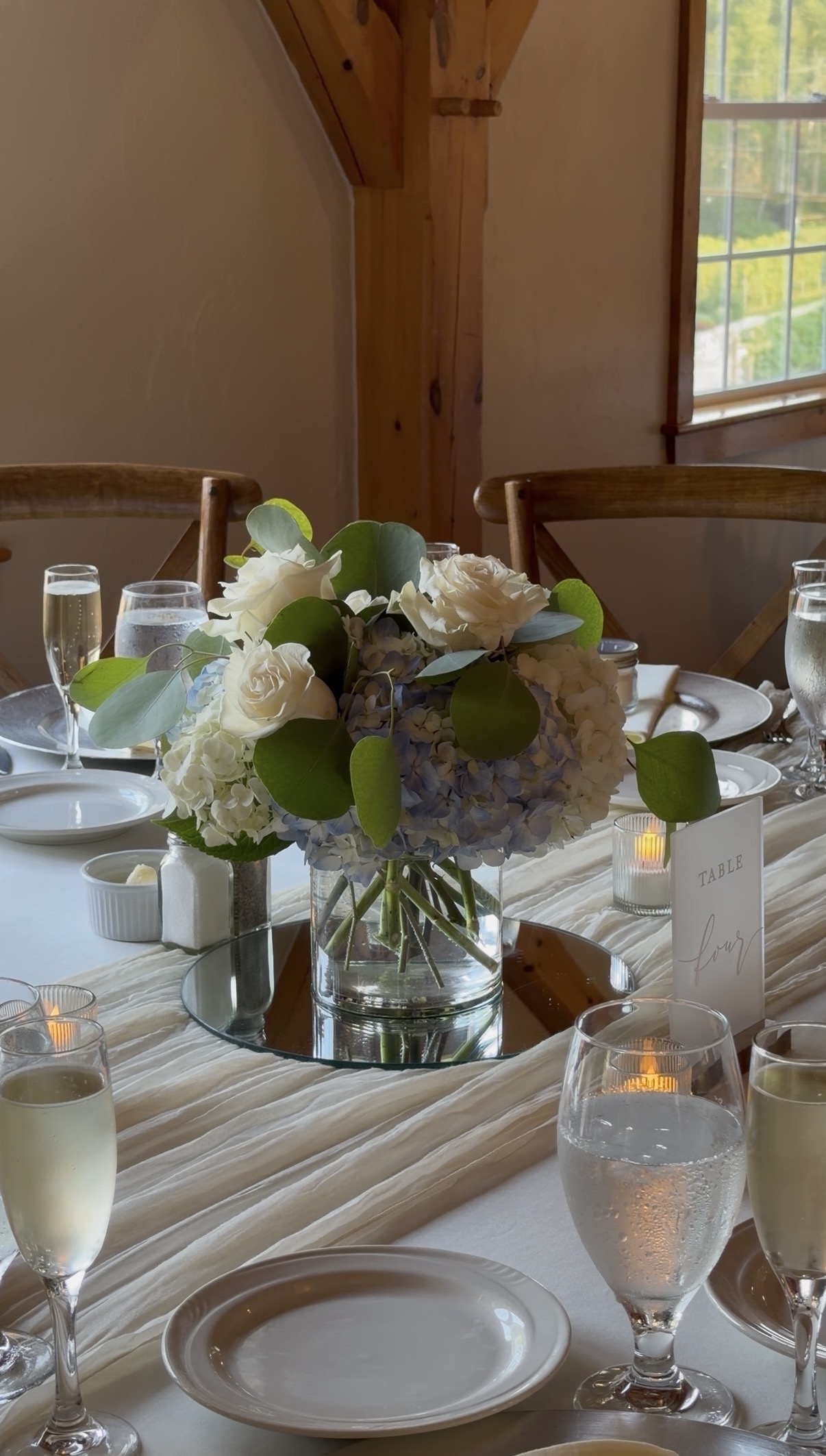Blue and white hydrangea centerpiece with eucalyptus at a family vineyard wedding reception at Zorvino Vineyards Blue and white hydrangea, soft eucalyptus, and candlelight, exactly as simple as they wanted it.