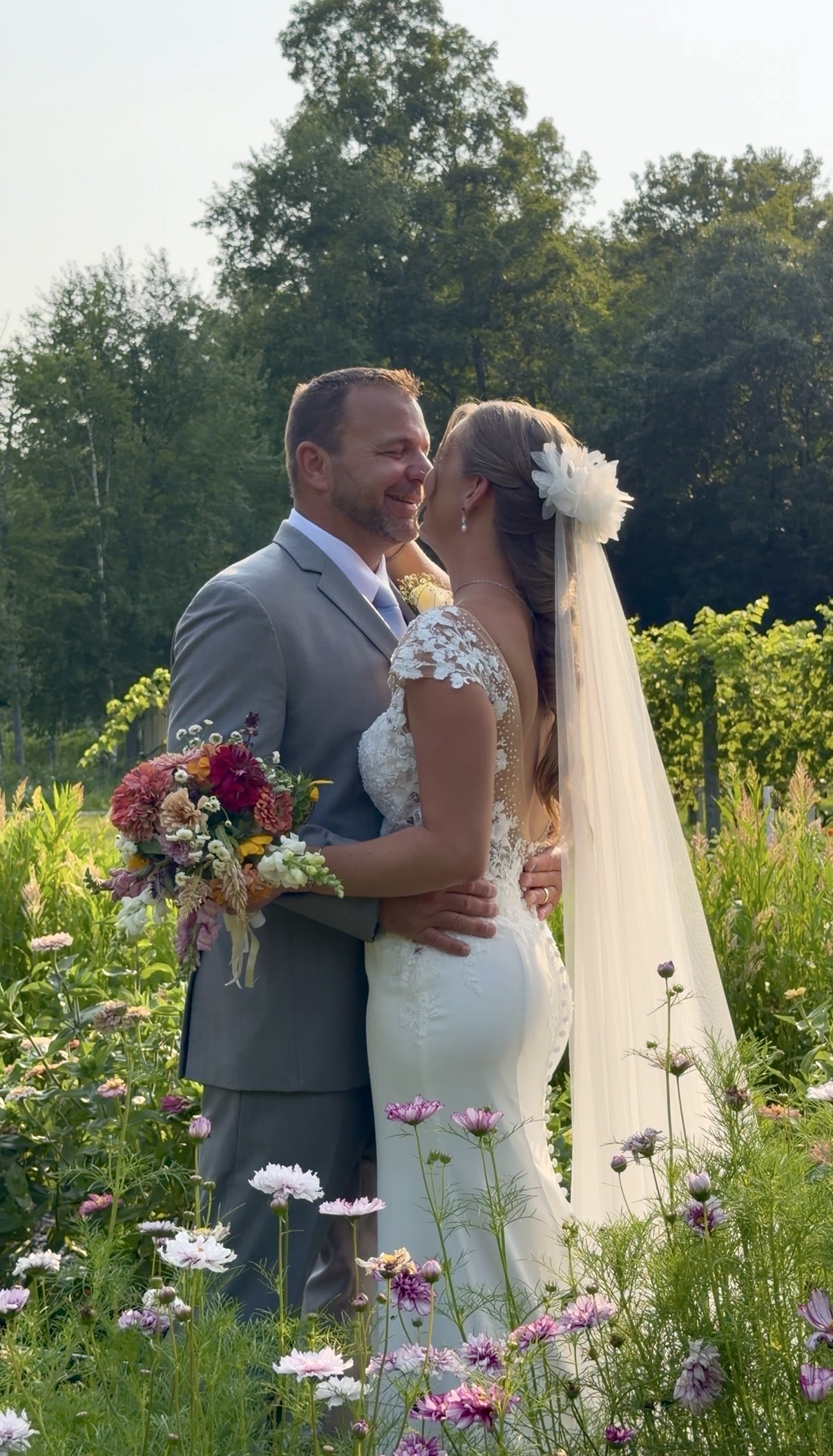 Bride and groom in Zorvino's wildflower garden with a colorful bouquet at their summer family vineyard wedding in New Hampshire In Zorvino's wildflower garden, where the bouquet almost disappeared right into the blooms.