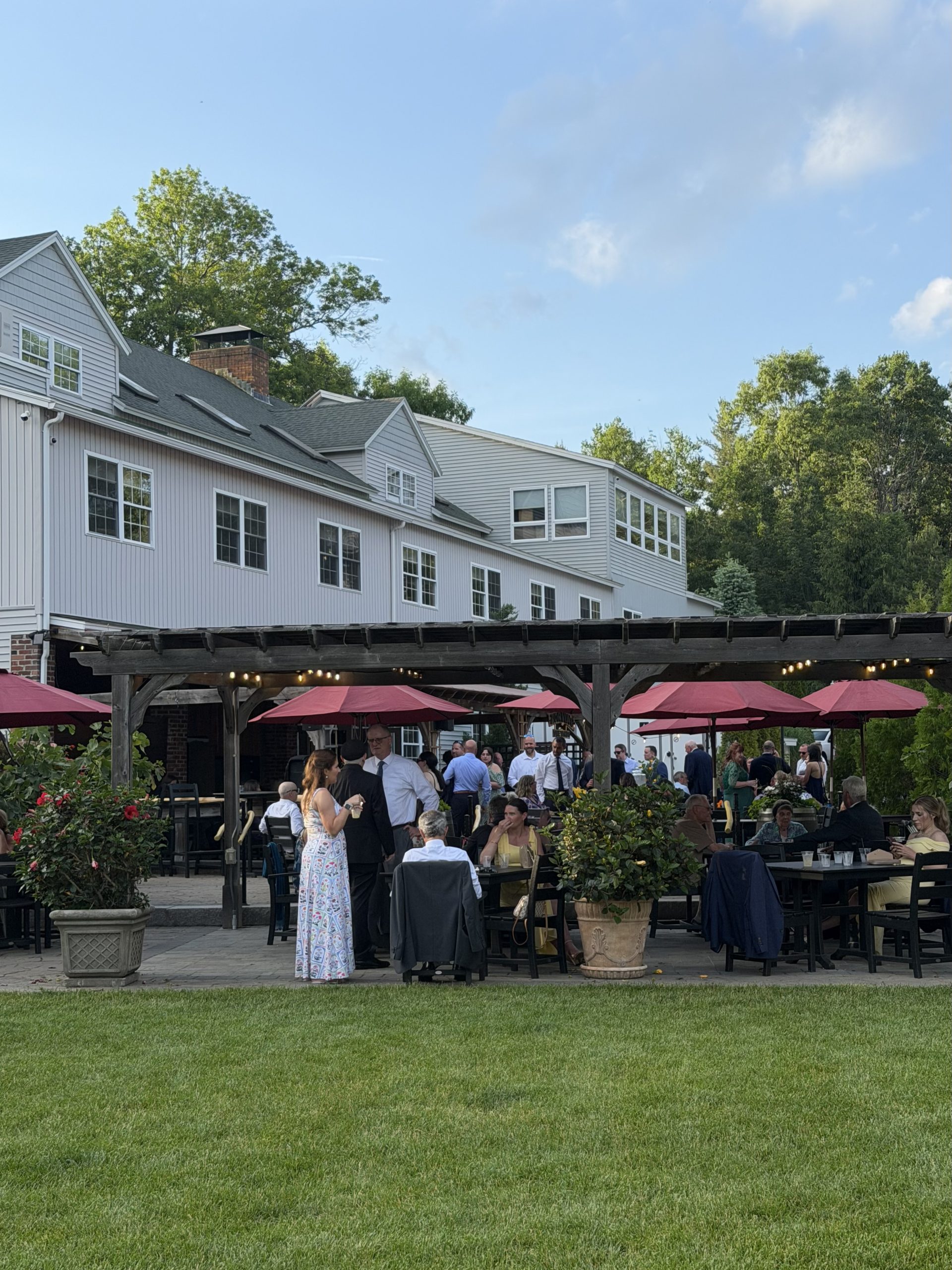 Outdoor patio cocktail hour with burgundy umbrellas at a sage and wildflower wedding at Zorvino Vineyards NH