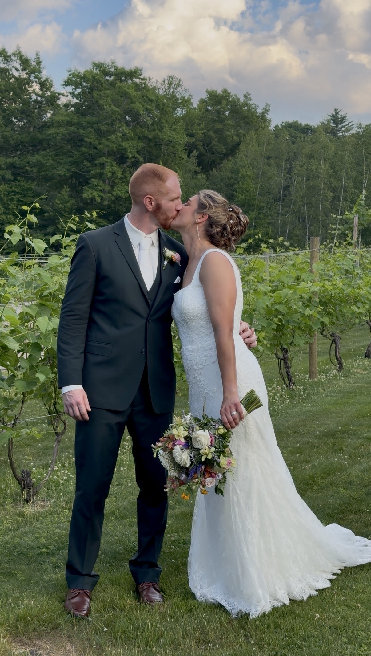 Bride and groom kiss in the vineyard rows at a sage and wildflower wedding at Zorvino Vineyards NH