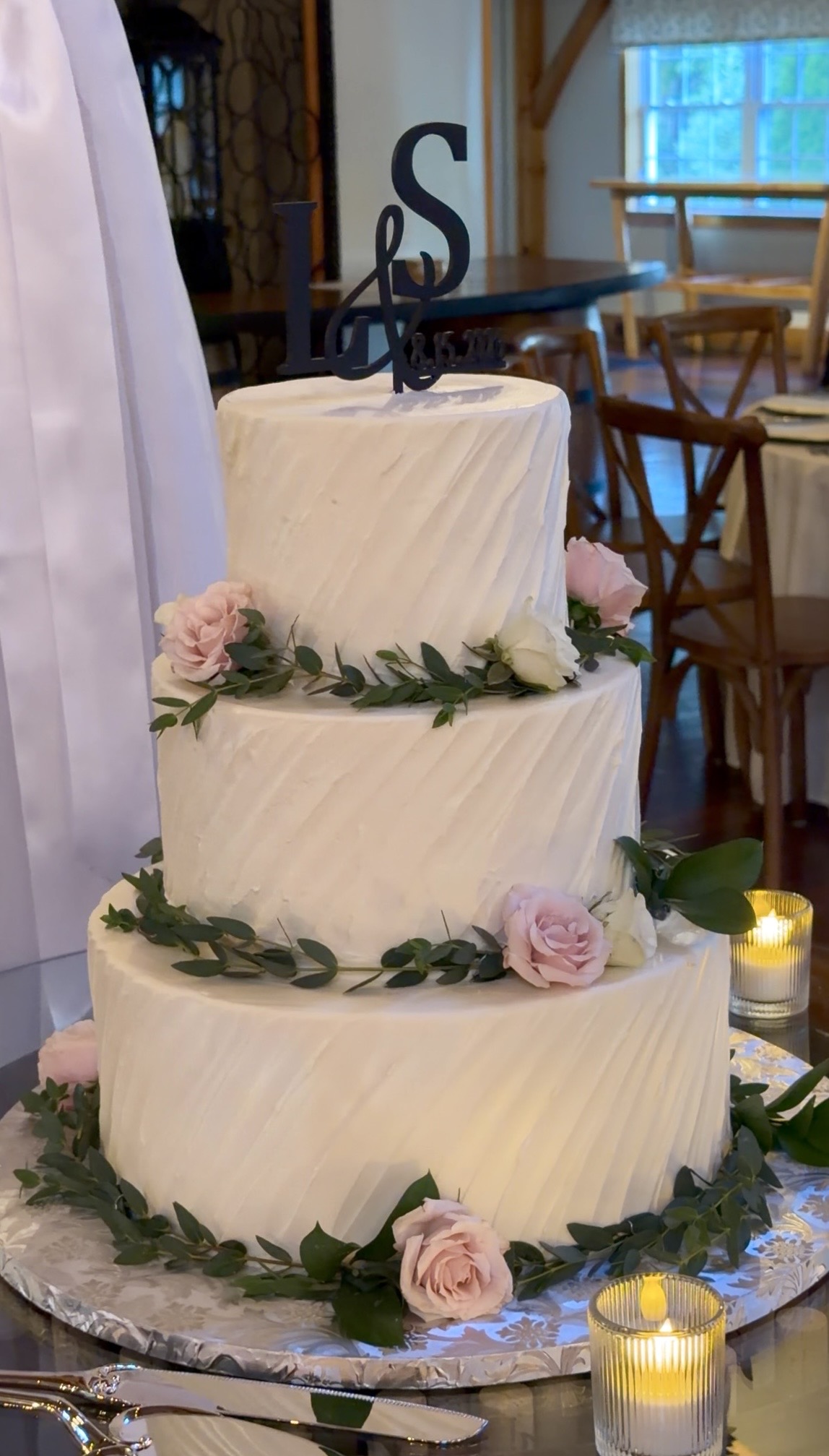Three-tier white wedding cake with blush roses and eucalyptus at a summer garden vineyard wedding at Zorvino Vineyards