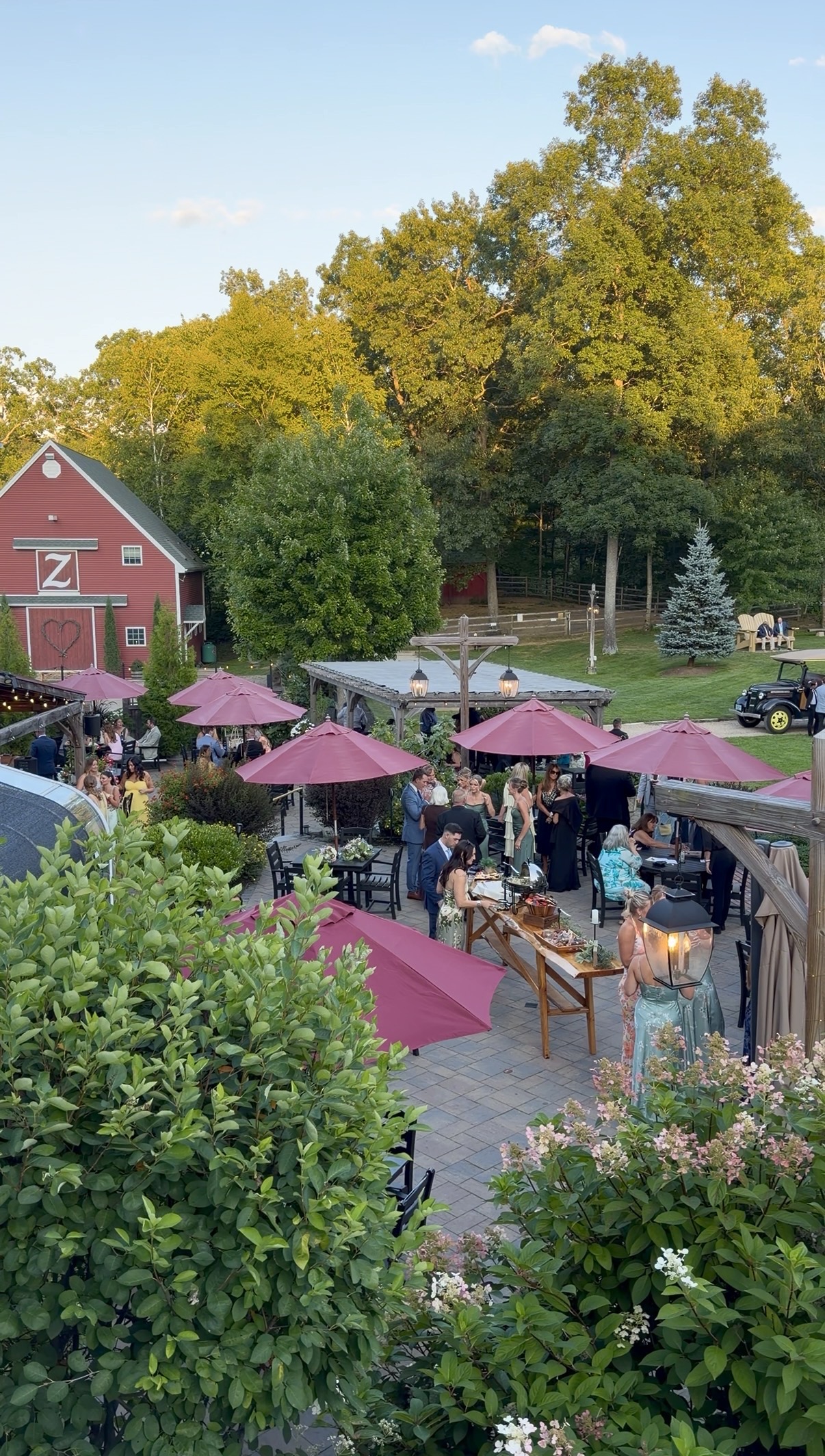 Outdoor patio cocktail hour beside the red barn at a summer garden vineyard wedding at Zorvino Vineyards