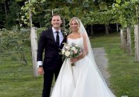Lilly and Steven beneath Zorvino's grape arbor at their summer garden vineyard wedding in Sandown, NH