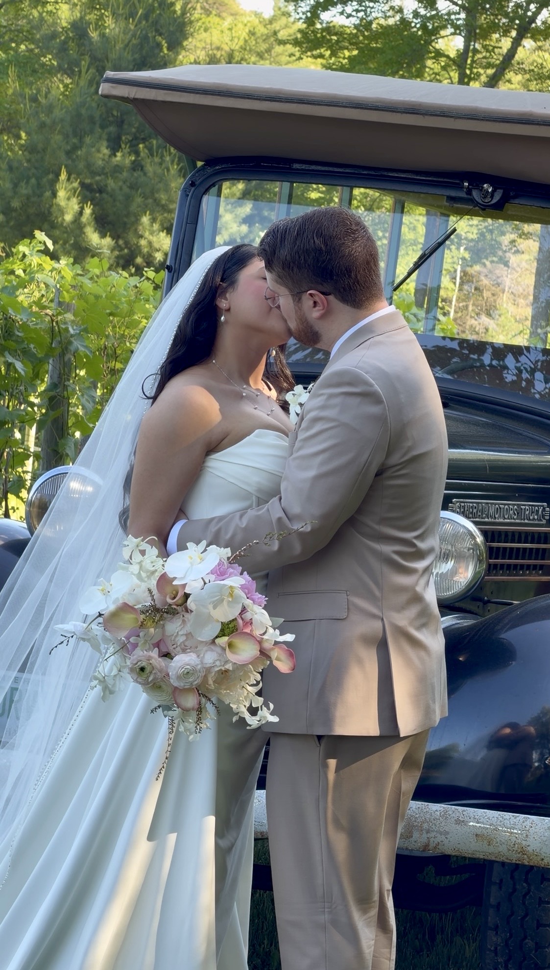 Bride and groom kiss beside a vintage truck at a vineyard pavilion wedding at Zorvino Vineyards
