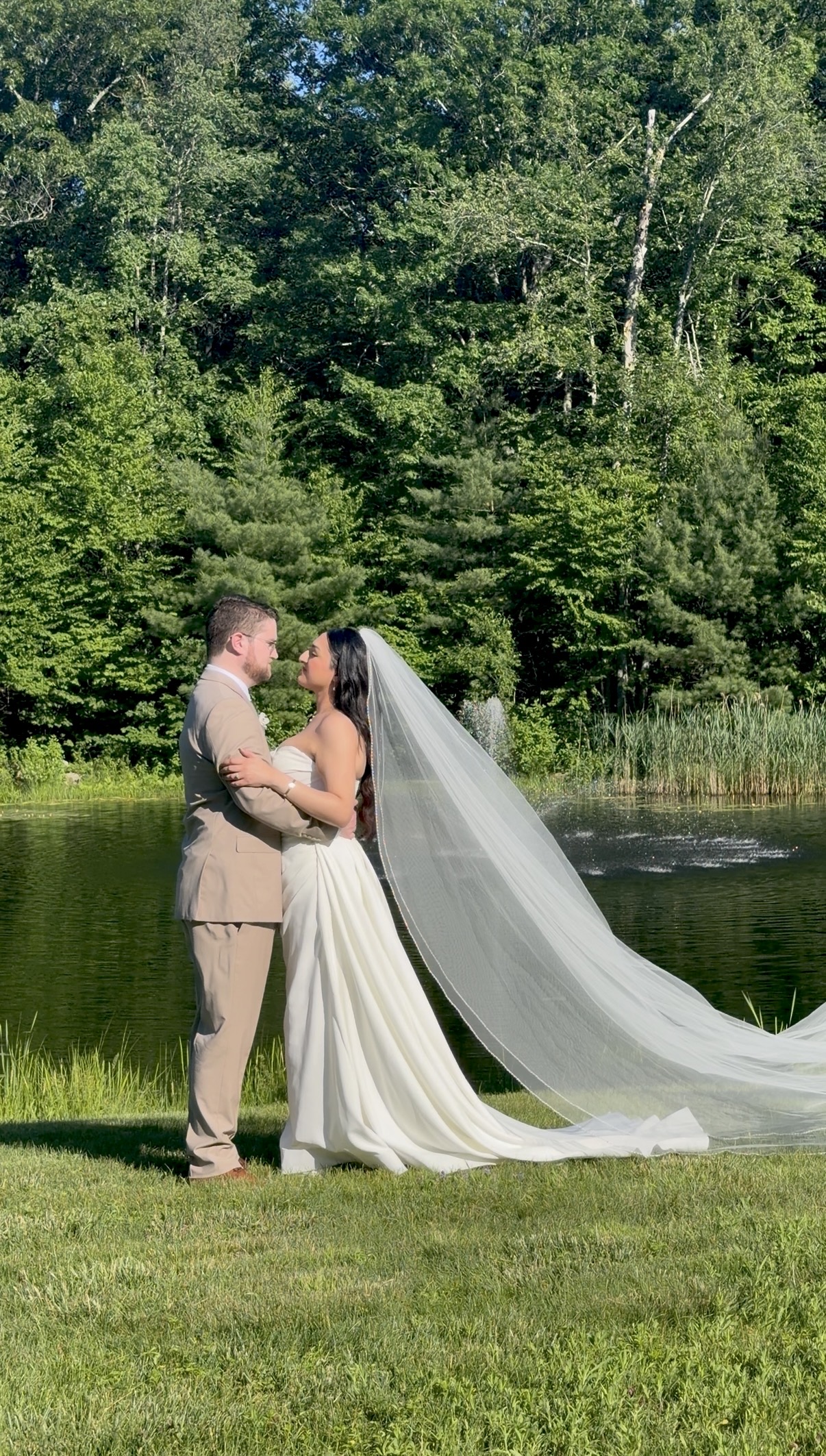 Bride with cathedral veil and groom by the pond at a vineyard pavilion wedding at Zorvino Vineyards Image